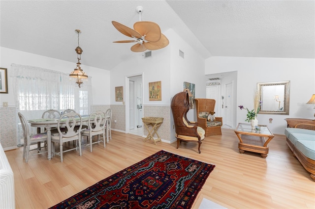 dining room featuring visible vents, a wainscoted wall, vaulted ceiling, and a textured ceiling