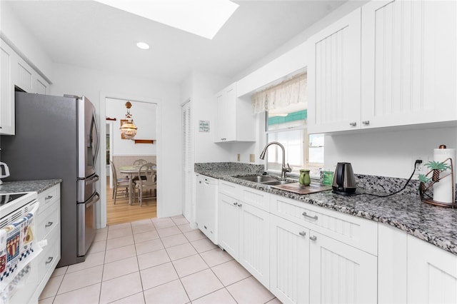 kitchen featuring white appliances, stone counters, a sink, and white cabinetry