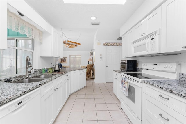 kitchen with white appliances, visible vents, white cabinetry, and a sink