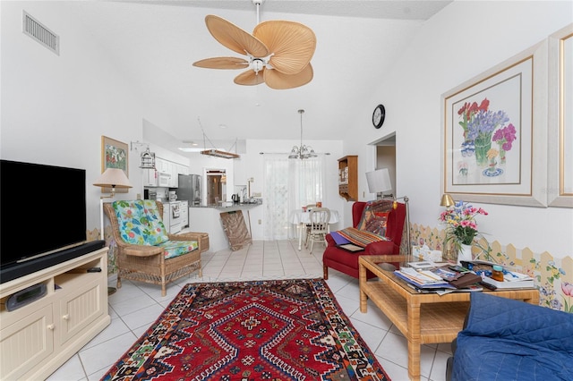 living area with ceiling fan with notable chandelier, visible vents, vaulted ceiling, and light tile patterned flooring