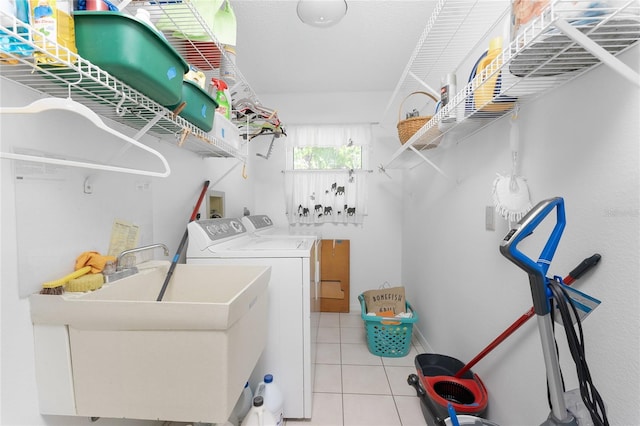 laundry room with light tile patterned floors, laundry area, washing machine and clothes dryer, and a sink