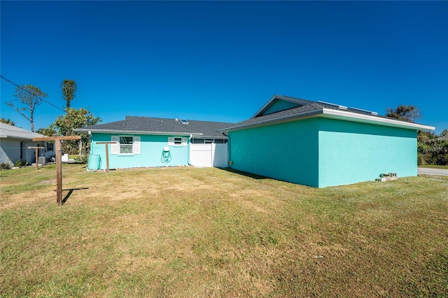 rear view of property featuring a lawn and stucco siding