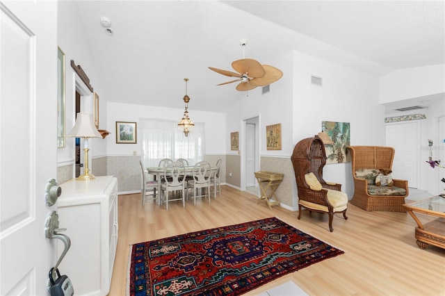 dining area featuring a wainscoted wall, visible vents, vaulted ceiling, and wood finished floors