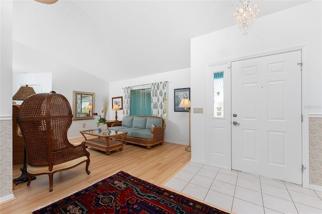 entryway with vaulted ceiling, a textured ceiling, light wood-type flooring, and a chandelier