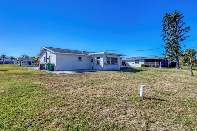 rear view of property featuring cooling unit, a patio area, and a yard