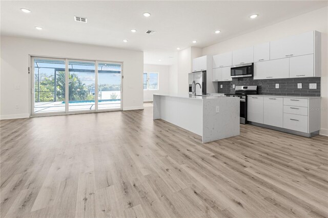 14681 Keystone Blvd, Port Charlotte, FL 33981 - kitchen featuring appliances with stainless steel finishes, light wood finished floors, open floor plan, white cabinets, and modern cabinets