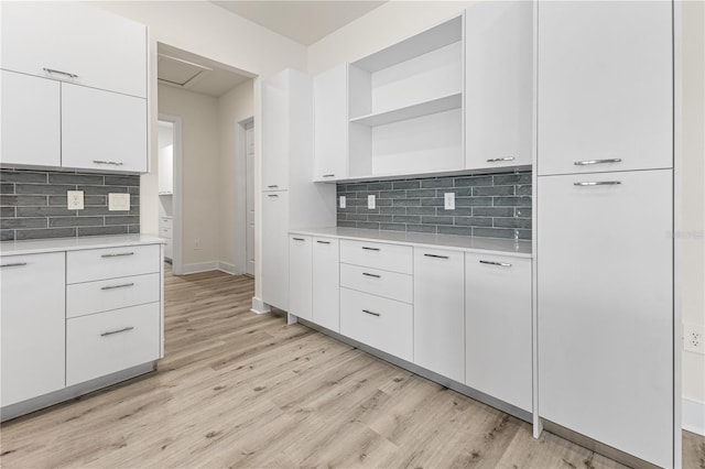 kitchen with backsplash, light hardwood / wood-style flooring, and white cabinets