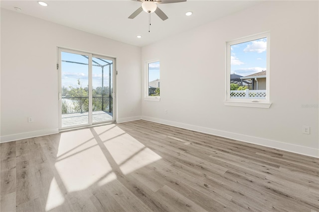 empty room featuring ceiling fan, a wealth of natural light, and light hardwood / wood-style flooring