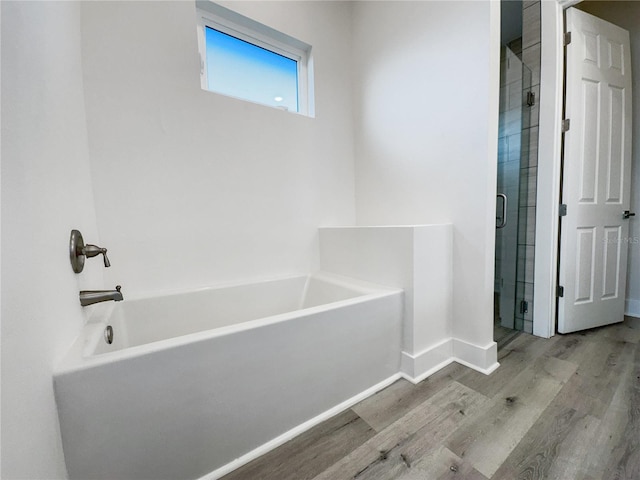 bathroom featuring plus walk in shower and wood-type flooring