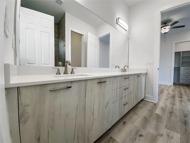 14681 Keystone Blvd, Port Charlotte, FL 33981 - bathroom featuring ceiling fan, double vanity, wood finished floors, baseboards, and a shower
