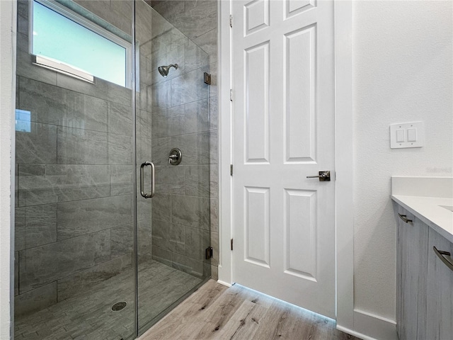 bathroom featuring hardwood / wood-style floors, vanity, and a shower with shower door