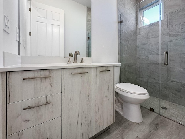 bathroom with hardwood / wood-style floors, vanity, toilet, and an enclosed shower