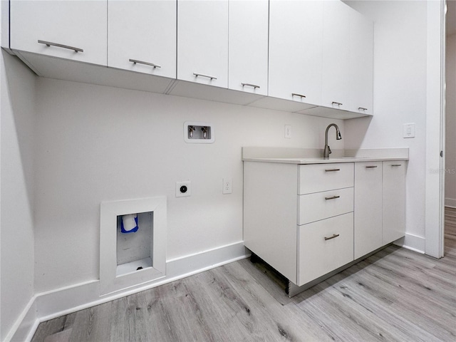 laundry room featuring electric dryer hookup, cabinets, light hardwood / wood-style floors, and washer hookup