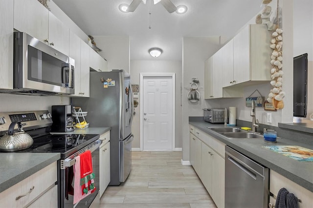 kitchen with light wood-type flooring, stainless steel appliances, ceiling fan, and sink