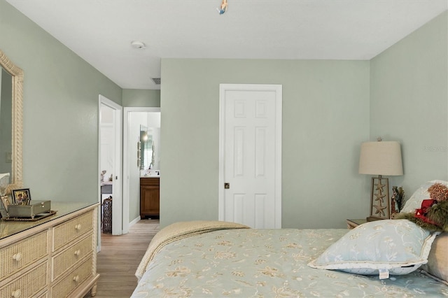 bedroom featuring light wood-type flooring and connected bathroom