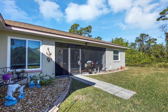 rear view of house with a lawn and a sunroom