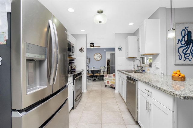 kitchen with appliances with stainless steel finishes, pendant lighting, white cabinetry, sink, and light stone countertops