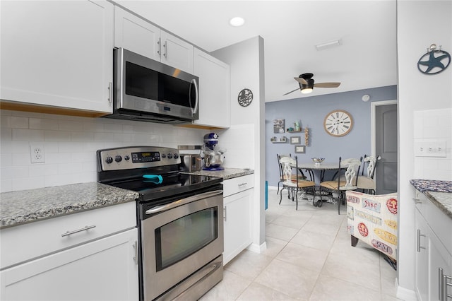 kitchen featuring light tile patterned floors, white cabinets, stainless steel appliances, light stone countertops, and backsplash