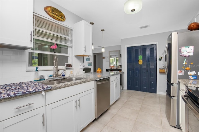 kitchen with white cabinetry, sink, dark stone countertops, hanging light fixtures, and stainless steel appliances