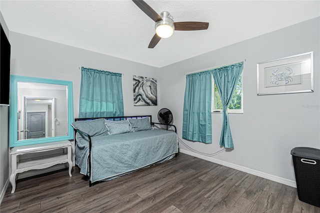 bedroom with dark hardwood / wood-style flooring, ceiling fan, and a textured ceiling