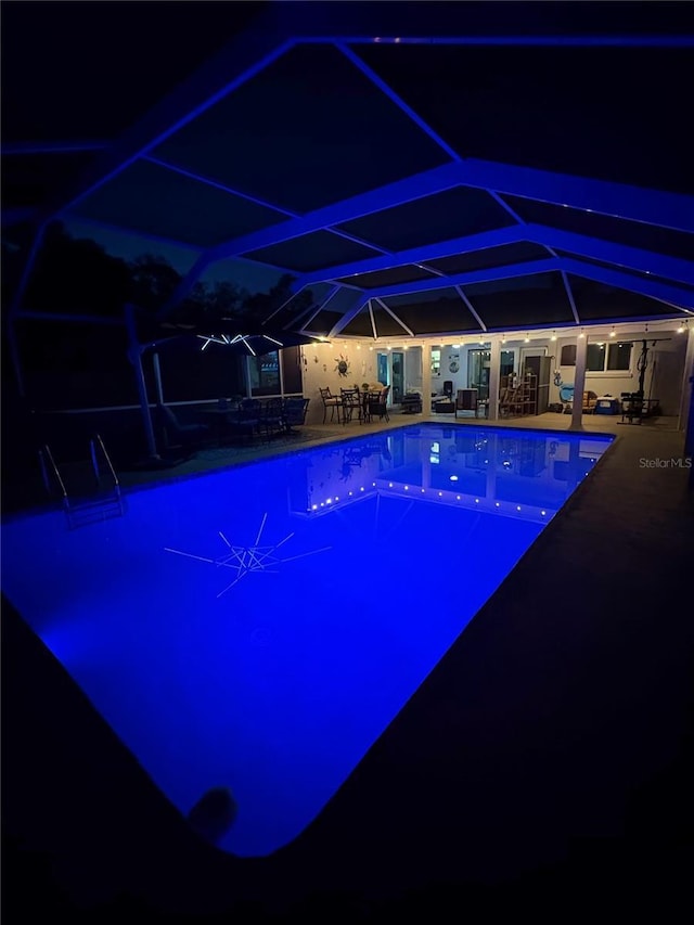 pool at twilight with a patio area and glass enclosure