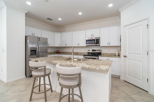 kitchen featuring stainless steel appliances, white cabinetry, a center island with sink, and sink