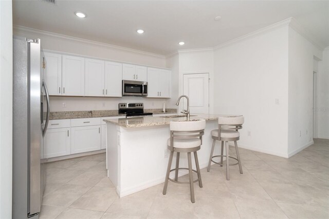 kitchen featuring sink, stainless steel appliances, white cabinetry, and an island with sink