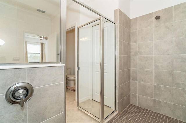 bathroom with tile patterned flooring, a tile shower, toilet, and ceiling fan