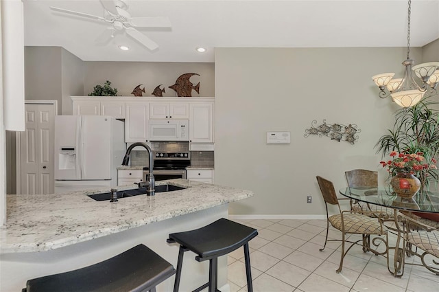 kitchen with decorative backsplash, white appliances, ceiling fan, sink, and white cabinetry