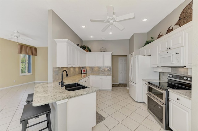 kitchen featuring white cabinetry, sink, kitchen peninsula, white appliances, and a kitchen bar