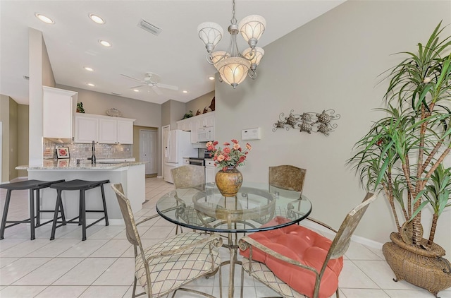 tiled dining space with ceiling fan with notable chandelier and sink