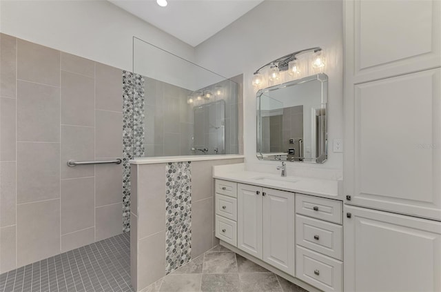 bathroom with vanity, a tile shower, and tile walls