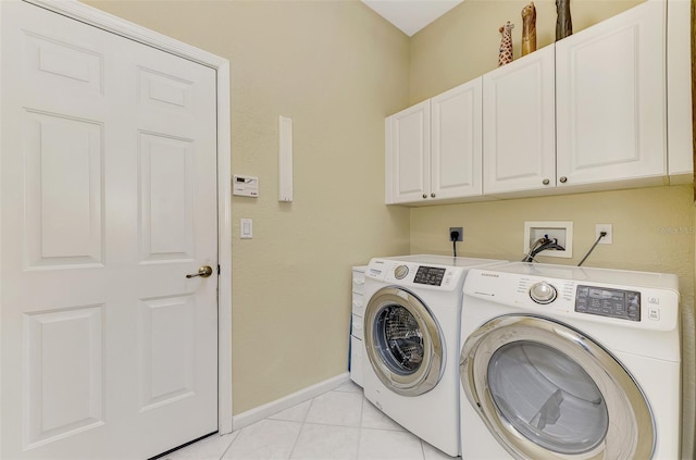 laundry area featuring washing machine and dryer, light tile patterned flooring, and cabinets