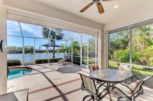 sunroom featuring ceiling fan and a water view