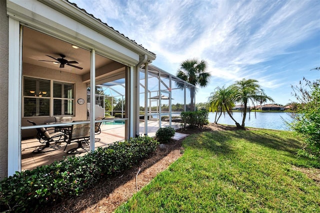 view of yard featuring a patio, a water view, ceiling fan, and a lanai