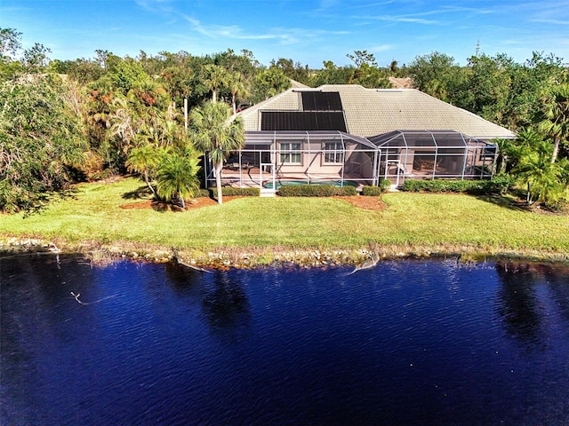 back of house with glass enclosure, a water view, a yard, and solar panels