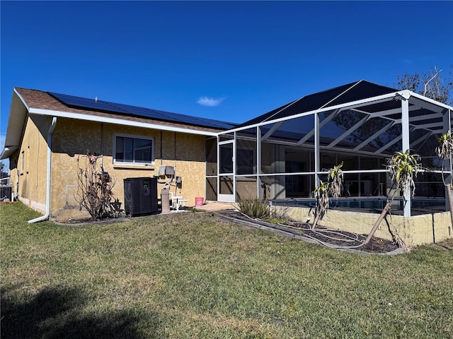 back of house with a lawn, a pool, a lanai, and solar panels