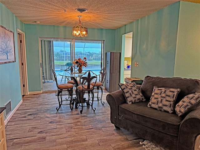 dining space with hardwood / wood-style floors, a textured ceiling, and an inviting chandelier