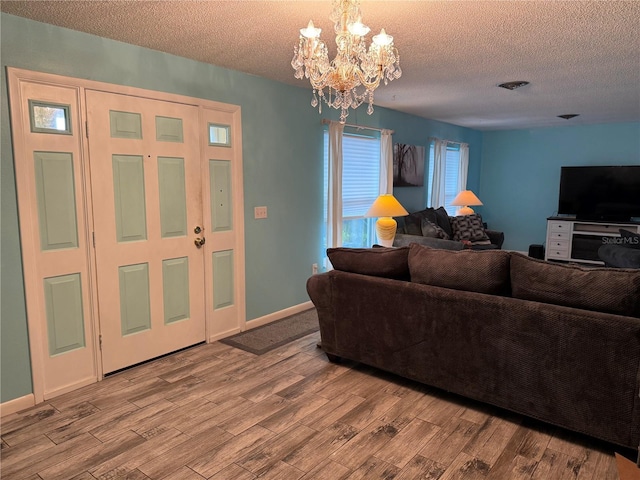 living room featuring a textured ceiling, light hardwood / wood-style floors, and a notable chandelier