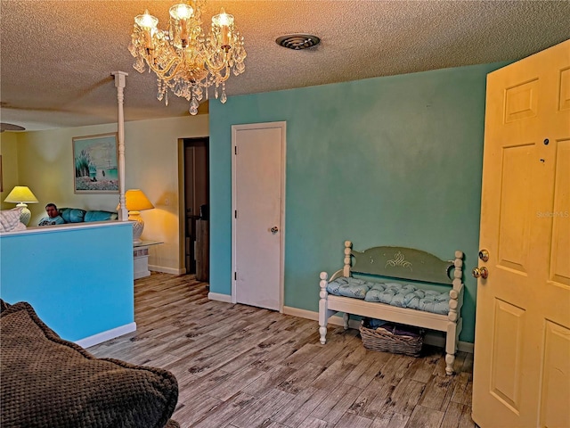 interior space with a textured ceiling, hardwood / wood-style flooring, and an inviting chandelier