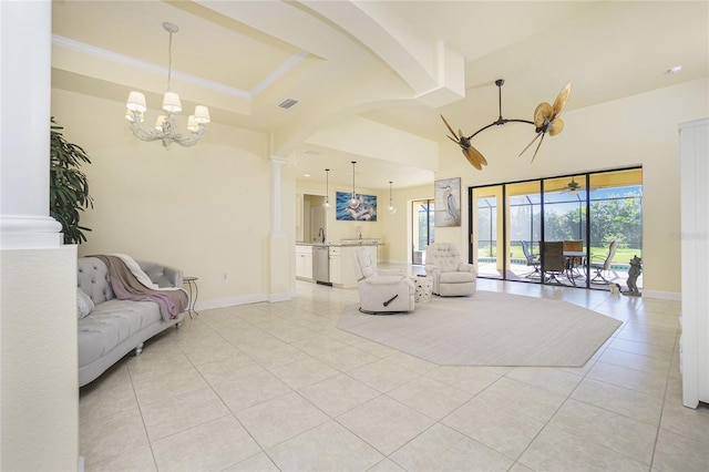 living room with light tile patterned floors, ceiling fan with notable chandelier, and decorative columns