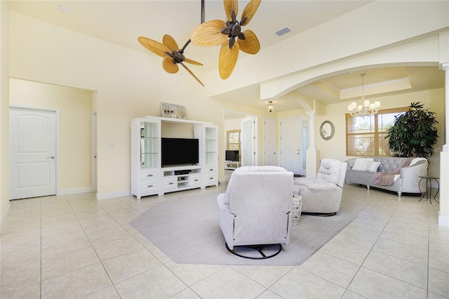 tiled living room with a tray ceiling and ceiling fan with notable chandelier