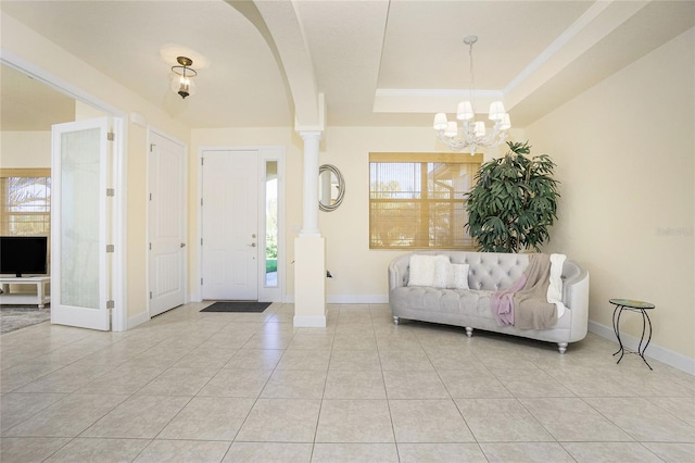 tiled foyer entrance with a tray ceiling, an inviting chandelier, and a healthy amount of sunlight