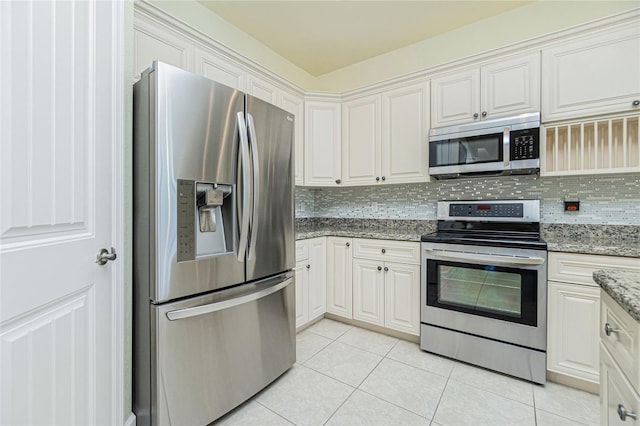 kitchen with light stone countertops, decorative backsplash, white cabinetry, and stainless steel appliances