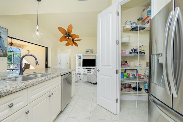 kitchen featuring sink, stainless steel appliances, light stone counters, decorative light fixtures, and white cabinets