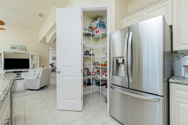 kitchen featuring light stone countertops, stainless steel fridge with ice dispenser, and light tile patterned floors