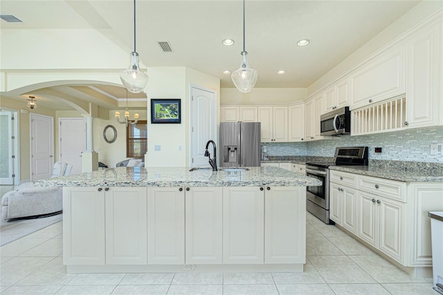 kitchen with white cabinetry, light stone countertops, decorative light fixtures, a center island with sink, and appliances with stainless steel finishes