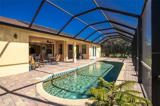 view of swimming pool featuring a patio, glass enclosure, and ceiling fan