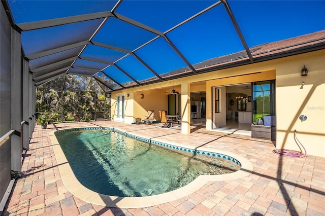 view of pool featuring glass enclosure, ceiling fan, and a patio area