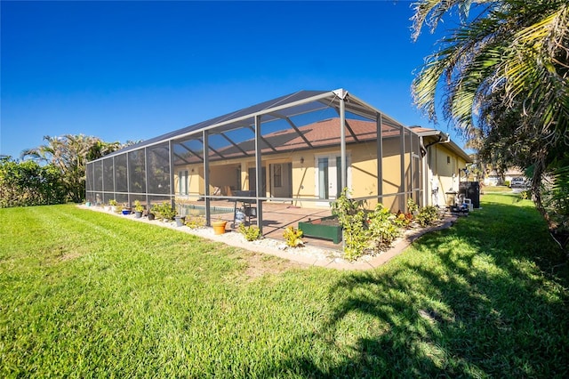 rear view of property with glass enclosure, a patio area, and a yard